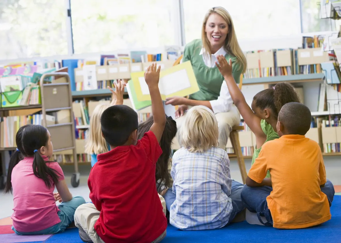 Kindergarten Teacher Reading to Children in a Library